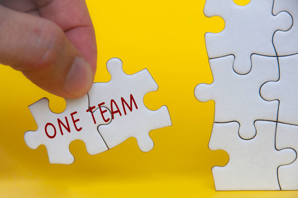 Hand houden ontbrekende puzzel met One Team tekst. Teamwork concept. - Foto, afbeelding