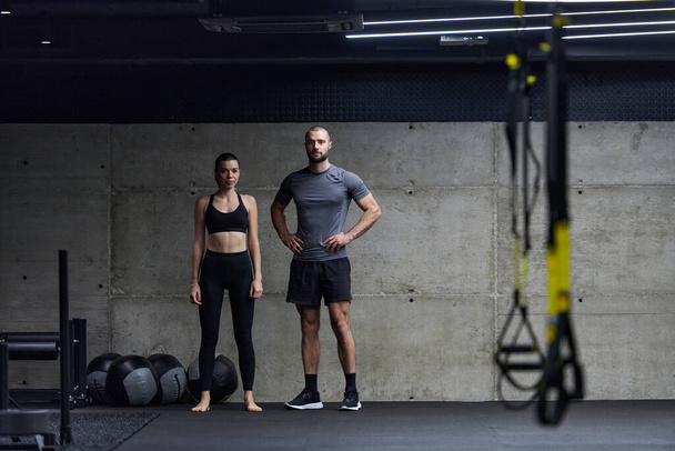 Muscular man and fit woman in a conversation before commencing their training session in a modern gym - Foto, Imagem