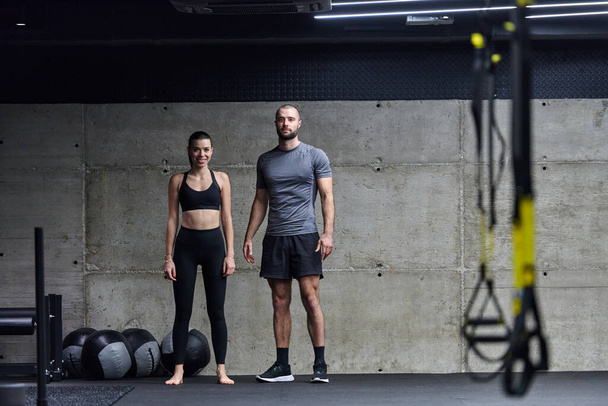 Muscular man and fit woman in a conversation before commencing their training session in a modern gym - Foto, afbeelding