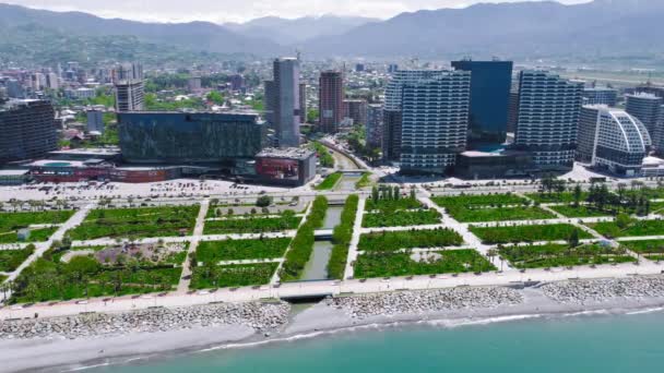 Drone uitzicht op prachtig park aan nieuwe boulevard op zonnige dag in Batumi, Adjara, Georgia. Zicht op zee en palmbomen. Moderne gebouwen en bergen. - Video
