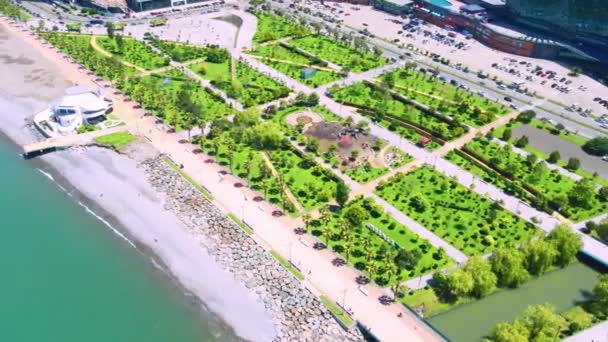 Drone uitzicht op prachtig park aan nieuwe boulevard op zonnige dag in Batumi, Adjara, Georgia. Zicht op zee en palmbomen. Moderne gebouwen en bergen. - Video