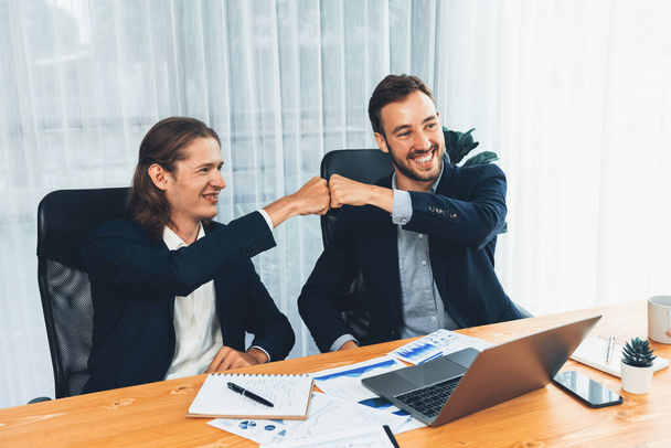 Businessmen celebrate success with joyous expressions, celebratory fist gesture in office after analyzing data or achieving target. Teamwork and planning lead to successful outcome. Entity - Фото, зображення
