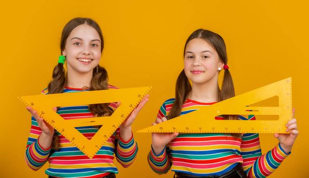 smiling school kids hold math tool of triangle. - Foto, Bild