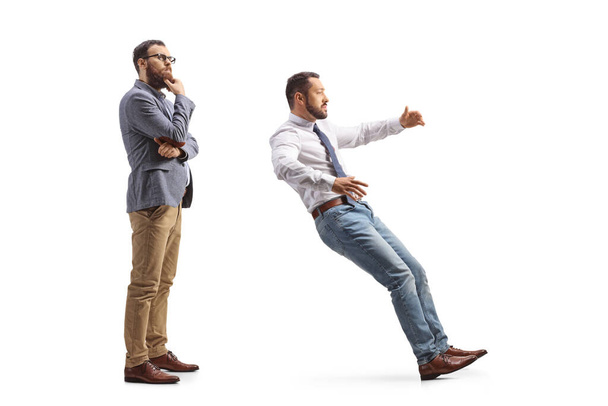 Full length profile shot of a pensive man standing behind a man falling isolated on white background - 写真・画像