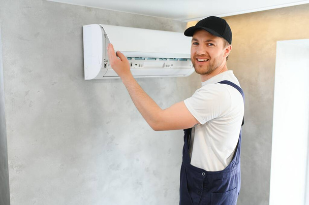 Happy Male Technician Repairing Air Conditioner - Foto, afbeelding