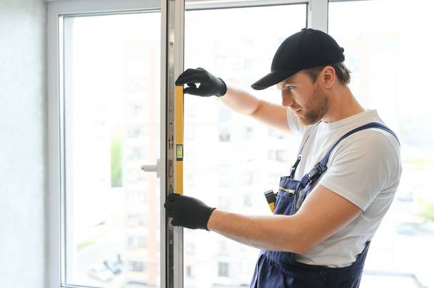 handsome young man installing bay window in new house construction site. - 写真・画像