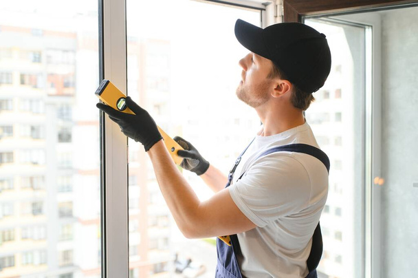 Construction worker repairing plastic window indoors, space for text. Banner design. - Zdjęcie, obraz
