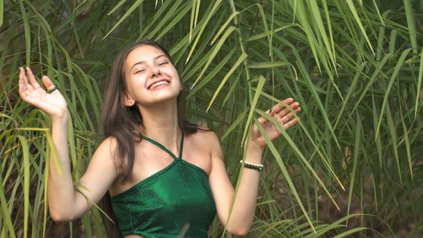 Etrafı tropik ormanlarla çevrili yeşil mayo giymiş mutlu genç bir kadın. Yüksek kalite fotoğraf - Fotoğraf, Görsel