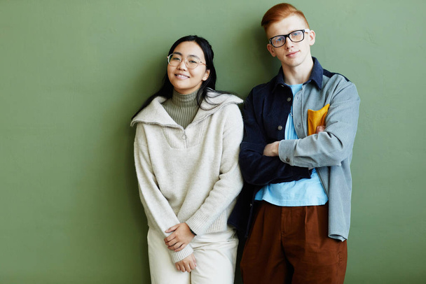 Candid waist up portrait of creative couple looking at camera while standing against green wall - Foto, Bild