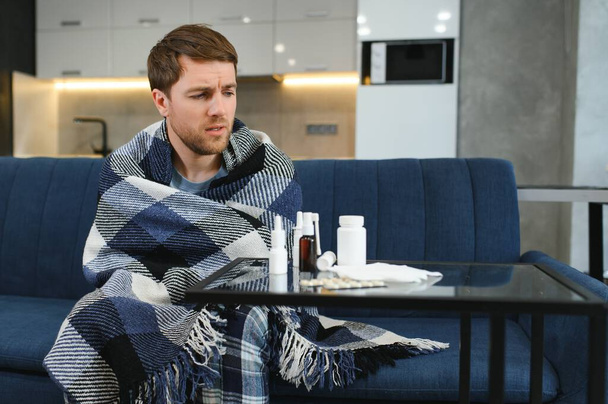 Man wrapped in plaid on the sofa feeling sick illness at home. - Foto, immagini