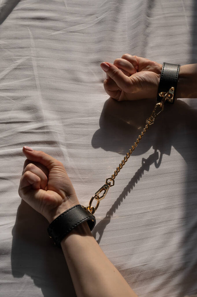 Close-up of womans hands in leather handcuffs. Sex toy - Fotoğraf, Görsel