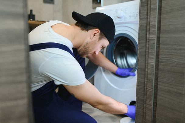 Technician repairing a washing machine. - Фото, изображение