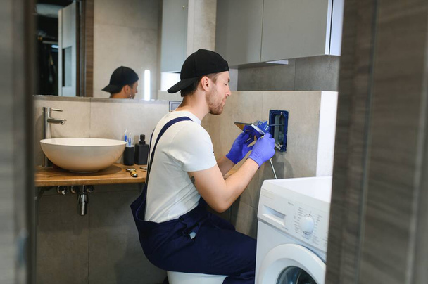 Professional plumber working with toilet bowl in bathroom. - Foto, Bild