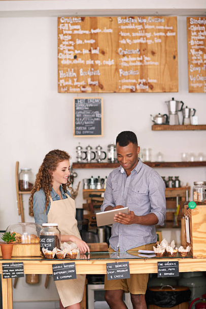 Coffee shop owners, tablet and teamwork of people, manage orders and discussion in store. Waiters, black man and happy woman in cafe with technology for inventory, stock check and managing sales - Photo, Image