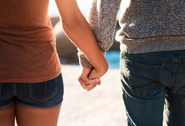 Love, beach and closeup of couple holding hands for relaxing, bonding and quality time. Nature, travel and man and woman together for anniversary or honeymoon on holiday, weekend and vacation by sea. - Photo, Image