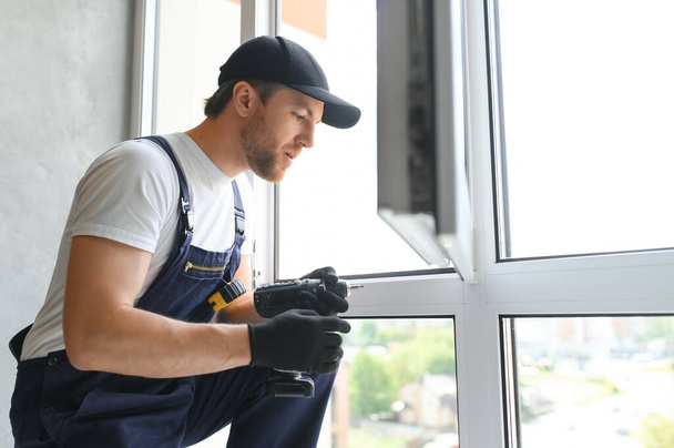Construction worker repairing plastic window indoors, space for text. Banner design. - Photo, image