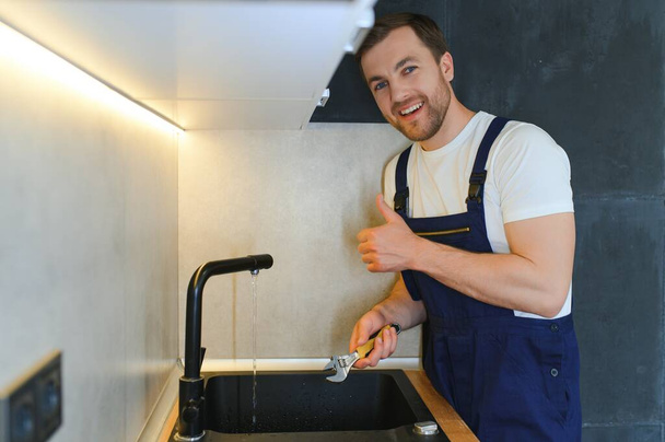 Professional plumber fixing water tap in kitchen. - Foto, Imagem