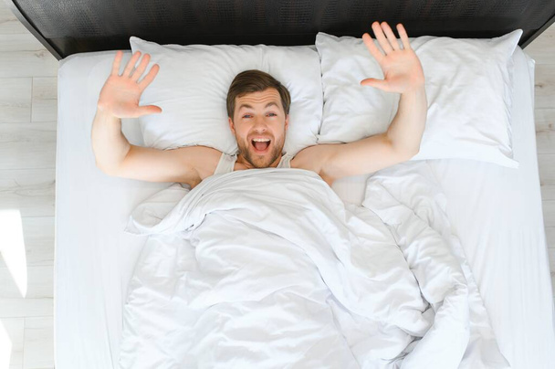 Cheerful Man Waking Up Lying In Cozy Bed At Home On Weekend Morning. Healthy Sleep Concept. - Фото, зображення