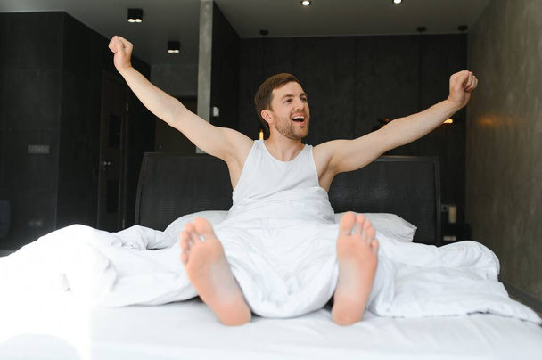 Cheerful Man Waking Up Lying In Cozy Bed At Home On Weekend Morning. Healthy Sleep Concept. - Fotoğraf, Görsel