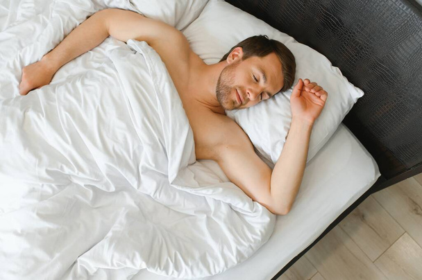 Cute young man sleeping on bed. - Fotografie, Obrázek