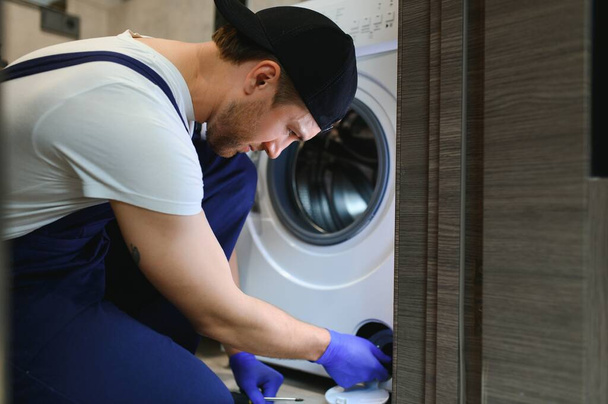 working man plumber repairs a washing machine. - Foto, Bild