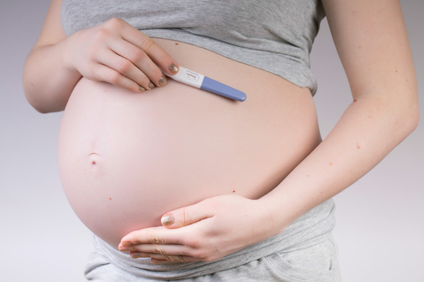 Mujer embarazada sosteniendo el vientre en la prueba positiva
 - Foto, imagen