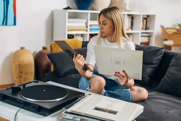 A woman chooses what record to play on gramophone - Φωτογραφία, εικόνα