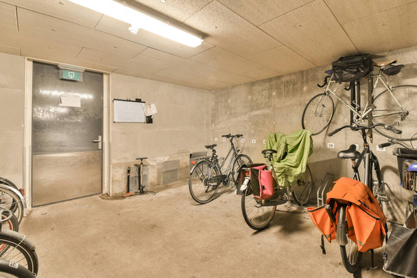 joitakin polkupyöriä huoneessa, jossa ei ole ketään seinällä tai katossa, ja on avoin ovi, joka johtaa toiseen huoneeseen - Valokuva, kuva