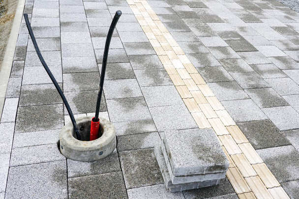 Nově dlážděná chodník s pokyny pro zrakově postižené a betonové základny s kabelové zásuvky pro světelné tyče, hmatové dlažby - Fotografie, Obrázek
