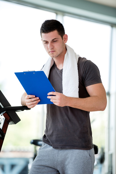 Trainer with clipboard standing in a bright gym - Foto, afbeelding