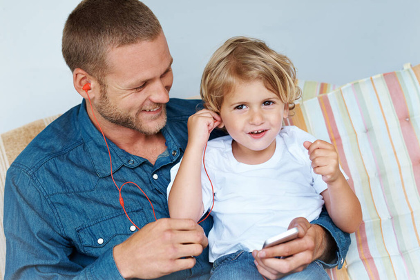 Rocking out with Dad. an adorable little boy sharing headphones with his father - Photo, Image