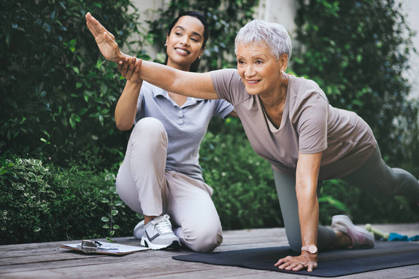 Возобновленная жизнь. пожилая женщина делает легкие упражнения во время сеанса с физиотерапевтом на улице - Фото, изображение