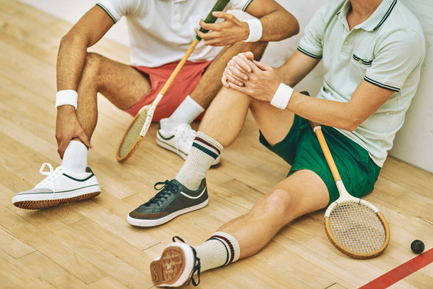Na een goede wedstrijd, komt een goede afkoeling. twee mannen nemen een pauze na het spelen van een spel squash - Foto, afbeelding