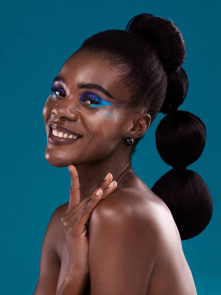 Portrait, smile and makeup with a model black woman in studio on a blue background for hair or cosmetics. Face, happy and fashion with an attractive young female person posing to promote beauty. - Fotografie, Obrázek