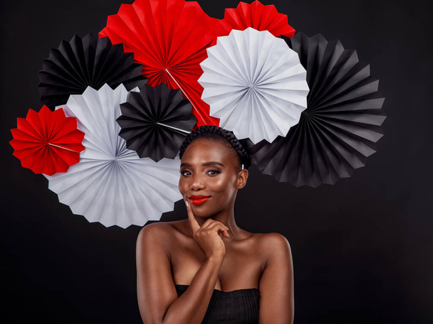 Beauty, portrait and black woman with origami fans in studio isolated on a dark background. Face, makeup cosmetics and skincare of female model with traditional Japanese paper art for culture hat - Zdjęcie, obraz