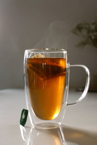 close up of a glas cup of black tea, flowers in blurred background  - Fotografie, Obrázek