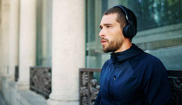 Get into the groove, get on the move. a young man listening to music during his workout in the city - Photo, Image