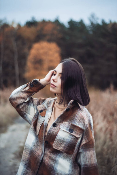 portrait of beautiful woman in a black sweater and hat posing in the woods. autumn portrait  - Fotó, kép