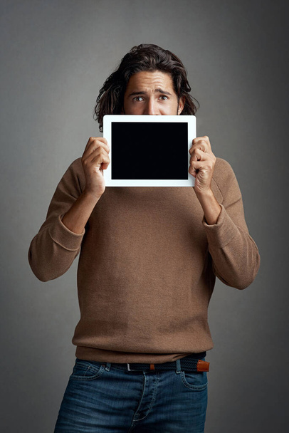 Obrazovka tabletu, maketa a portrét muže nakukujícího do studia izolovaného na šedém pozadí. Dotykový displej, vyděšený a muž s prostorem pro marketing, reklamu a technologie pro propagaci - Fotografie, Obrázek