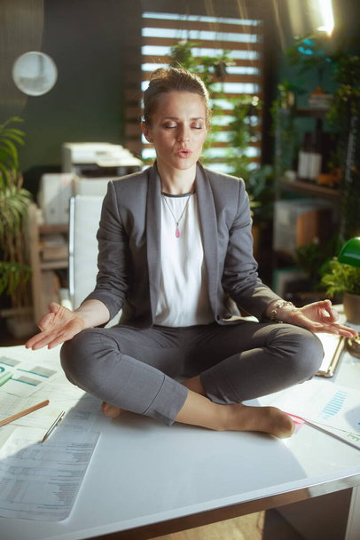 Sustainable workplace. relaxed modern business woman in modern green office meditating. - 写真・画像
