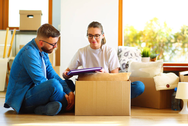 Happy young couple unpacking or packing boxes and moving into a new home. - Foto, imagen