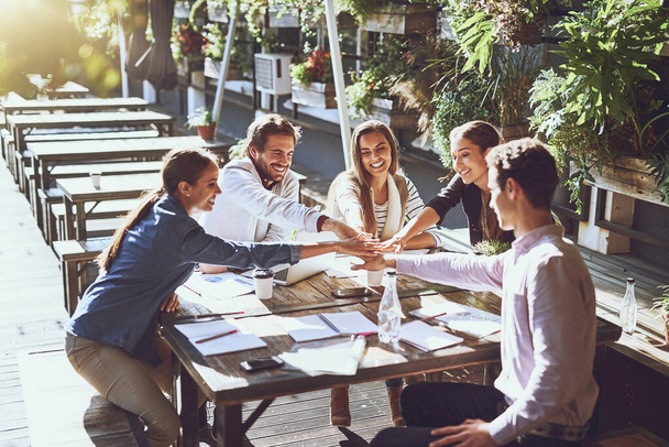 Its just better when you work together. a group of colleagues joining hands in agreement during a meeting at an outdoor cafe - Foto, Imagen