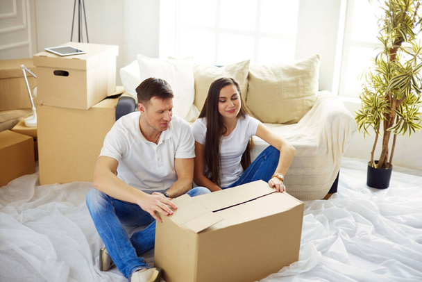 Happy young couple unpacking or packing boxes and moving into a new home. - Foto, immagini