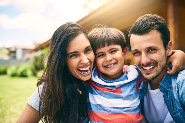 Happy family, portrait smile and hug for fun bonding, joy and relaxing together on holiday weekend outdoors. Mother, father and child face smiling and hugging in joyful happiness outside their house. - Photo, Image