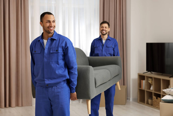 Male movers carrying sofa in new house - Photo, Image