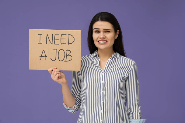 Munkanélküliségi probléma. Boldogtalan nő holding jel kifejezéssel I Need A Job on violet background - Fotó, kép
