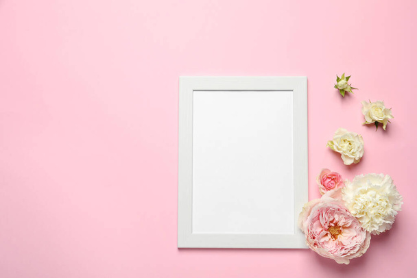 Empty photo frame and beautiful flowers on pink background, flat lay. Space for design - Фото, изображение
