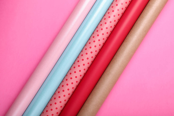 Rolls of colorful wrapping paper on pink background, flat lay - Foto, afbeelding