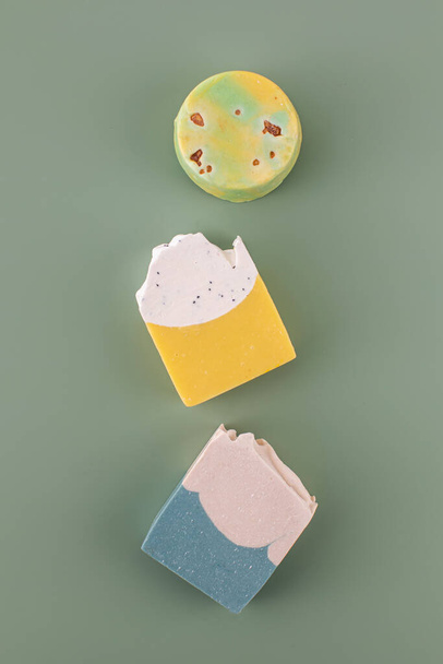 Pieces of different shapes and colors of handmade soap on a green background. The concept of natural cosmetics, hygiene. - Valokuva, kuva