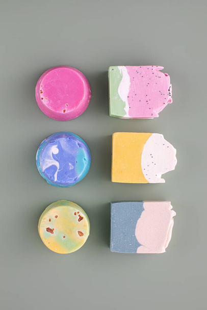 Pieces of different shapes and colors of handmade soap on a green background. The concept of natural cosmetics, hygiene. - Foto, Imagem